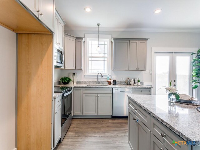 kitchen with a wealth of natural light, decorative light fixtures, sink, and appliances with stainless steel finishes