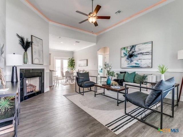 living room with a tile fireplace, crown molding, hardwood / wood-style floors, and ceiling fan