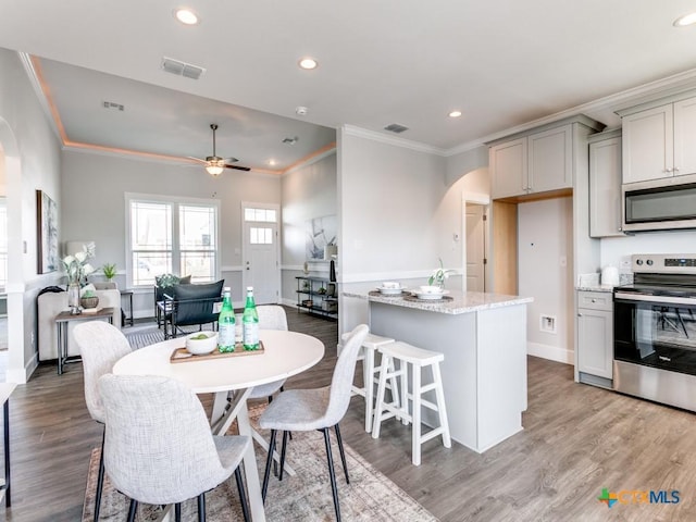 kitchen with light stone countertops, stainless steel appliances, ceiling fan, light hardwood / wood-style flooring, and gray cabinets