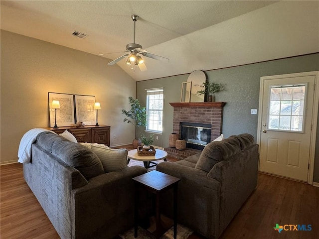 living room with hardwood / wood-style flooring, vaulted ceiling, a brick fireplace, and ceiling fan