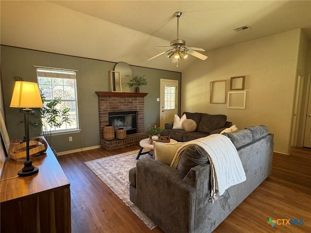 living room with ceiling fan, lofted ceiling, dark hardwood / wood-style flooring, and a brick fireplace