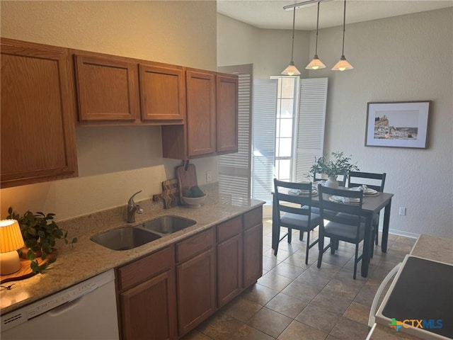 kitchen with hanging light fixtures, light stone countertops, sink, and white dishwasher