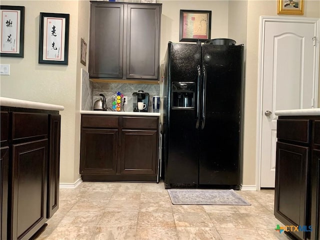 kitchen featuring light countertops, backsplash, dark brown cabinets, and black fridge