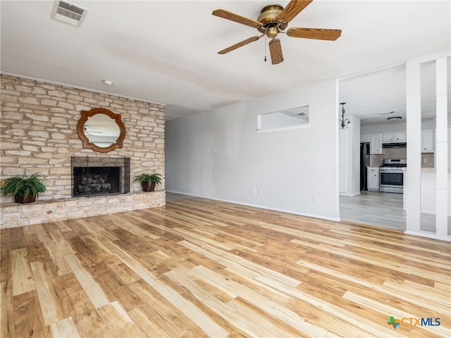 1304 Wroxton Way, Round Rock, TX 78664 - unfurnished living room featuring light wood finished floors, a ceiling fan, and a stone fireplace