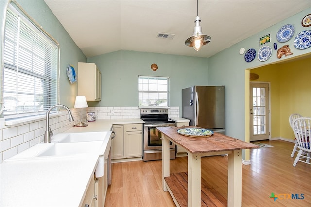 kitchen with backsplash, light hardwood / wood-style floors, stainless steel appliances, and hanging light fixtures