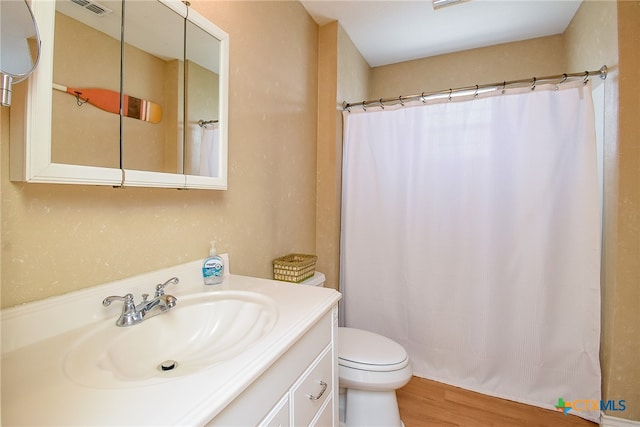 bathroom with toilet, vanity, and hardwood / wood-style flooring