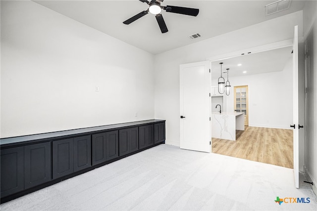 empty room featuring light wood-type flooring, ceiling fan, and sink