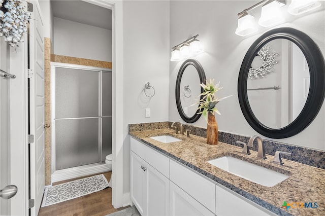 bathroom featuring hardwood / wood-style floors, a shower with shower door, vanity, and toilet