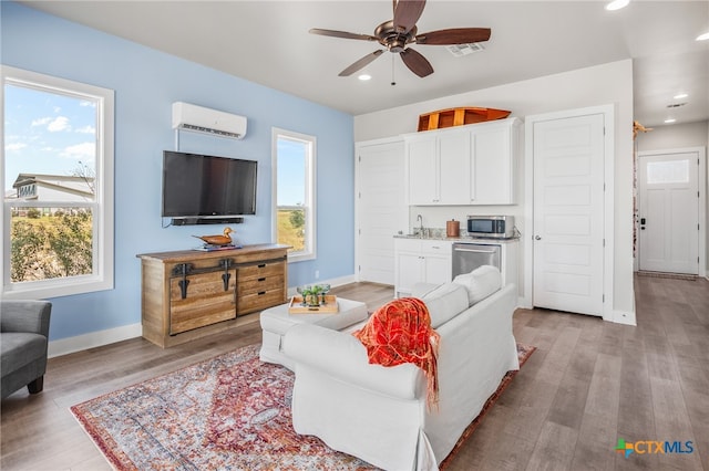 living room with light hardwood / wood-style floors, a wealth of natural light, and a wall mounted AC