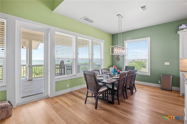 dining area featuring light hardwood / wood-style floors, a notable chandelier, and a healthy amount of sunlight