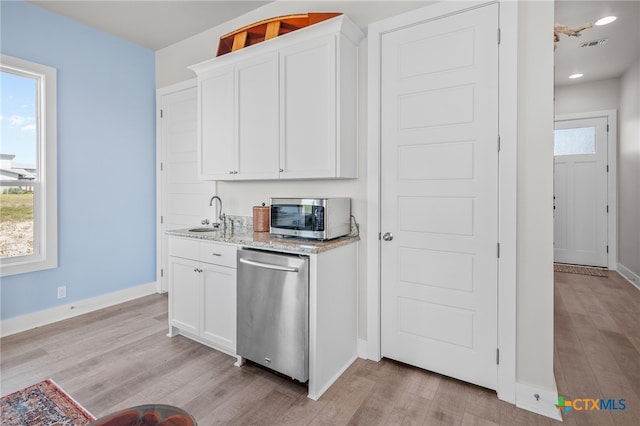 kitchen with stainless steel appliances, plenty of natural light, white cabinetry, and light wood-type flooring