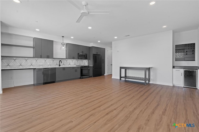 kitchen with backsplash, sink, wine cooler, light hardwood / wood-style flooring, and appliances with stainless steel finishes