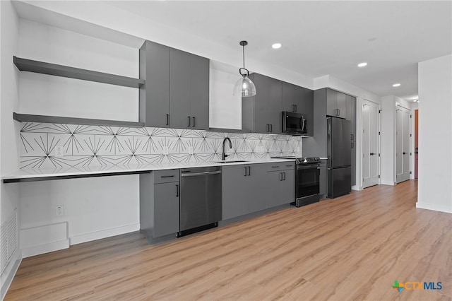 kitchen with light wood-type flooring, backsplash, stainless steel appliances, sink, and decorative light fixtures