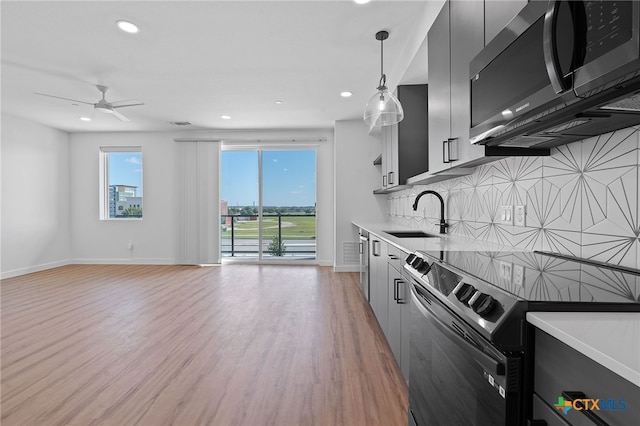 kitchen with pendant lighting, backsplash, sink, light hardwood / wood-style flooring, and appliances with stainless steel finishes