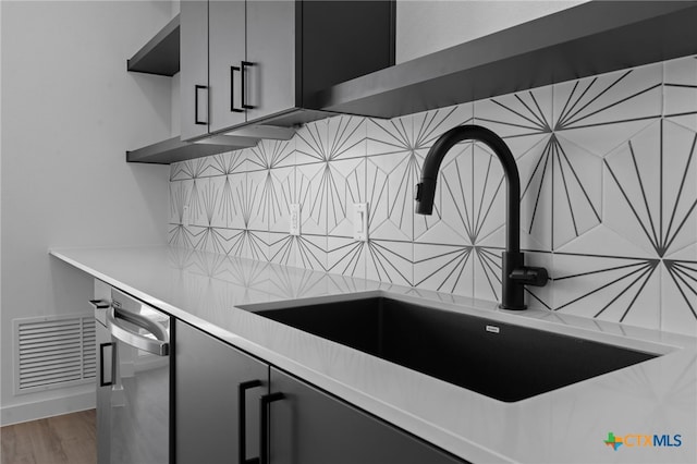 kitchen with decorative backsplash, hardwood / wood-style flooring, dishwasher, and sink