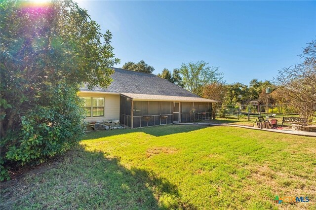 exterior space featuring a sunroom, a patio area, and a lawn