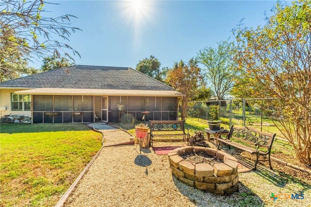 back of house featuring a sunroom, an outdoor fire pit, and a lawn