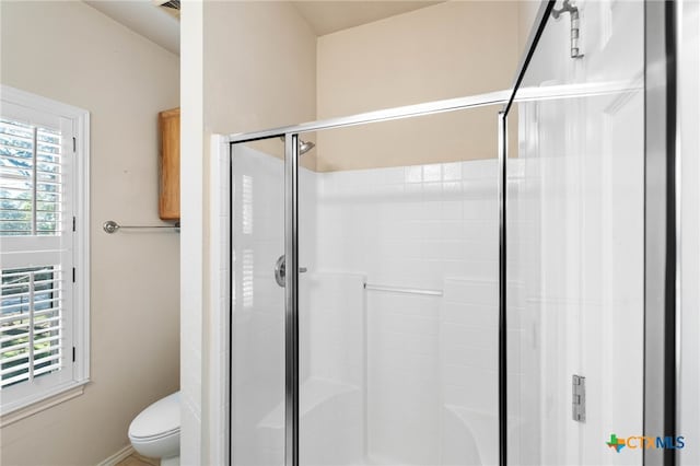 bathroom featuring toilet and a shower with door