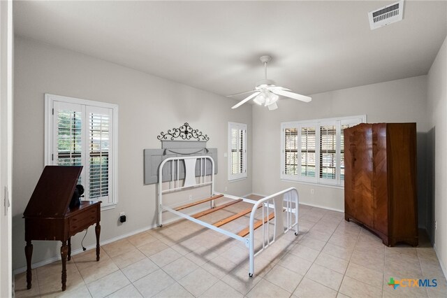 tiled bedroom with ceiling fan and multiple windows