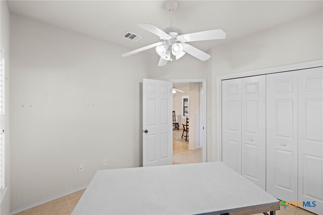 bedroom featuring ceiling fan, light tile patterned floors, and a closet