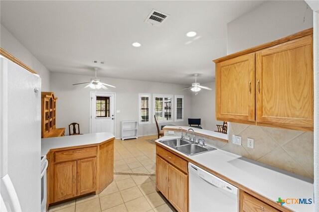 kitchen featuring kitchen peninsula, decorative backsplash, white appliances, sink, and light tile patterned floors