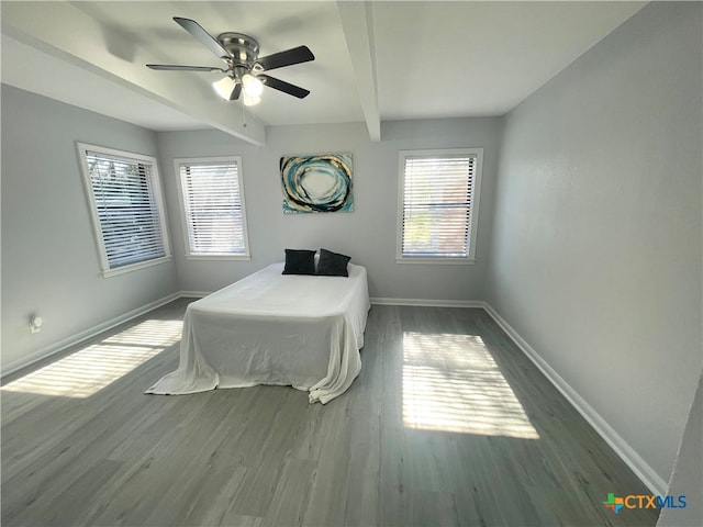 bedroom with ceiling fan, baseboards, beam ceiling, and wood finished floors