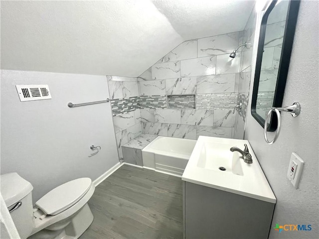 bathroom with wood finished floors, vaulted ceiling, toilet, vanity, and a textured ceiling