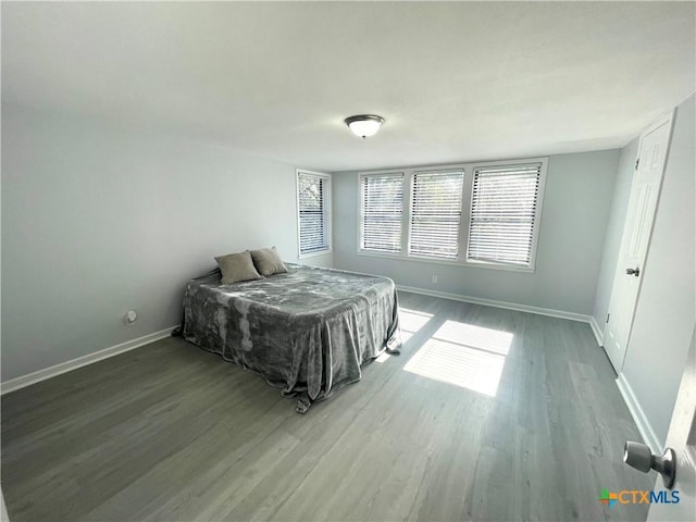 bedroom featuring baseboards, wood finished floors, and multiple windows