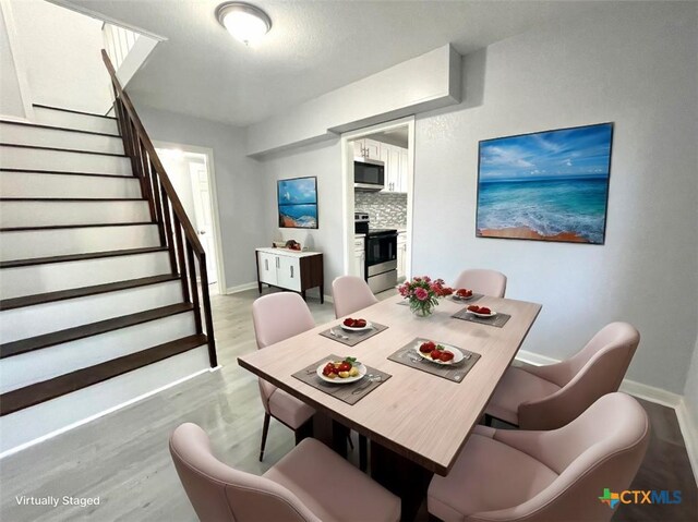 dining area featuring stairs, light wood-type flooring, and baseboards