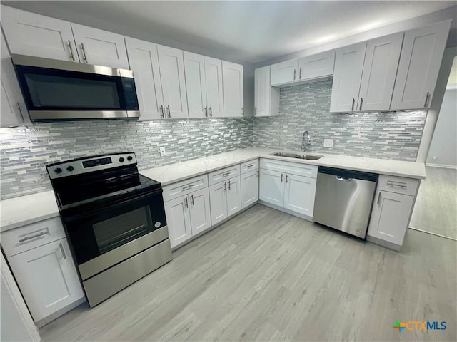 kitchen with decorative backsplash, light stone countertops, stainless steel appliances, light wood-style floors, and a sink