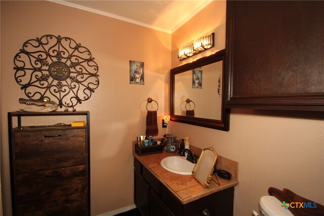 bathroom featuring toilet, vanity, and crown molding