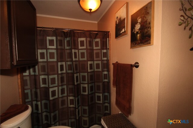 bathroom with toilet, curtained shower, and crown molding