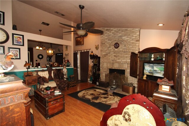 living room with hardwood / wood-style floors, a fireplace, ceiling fan, and vaulted ceiling