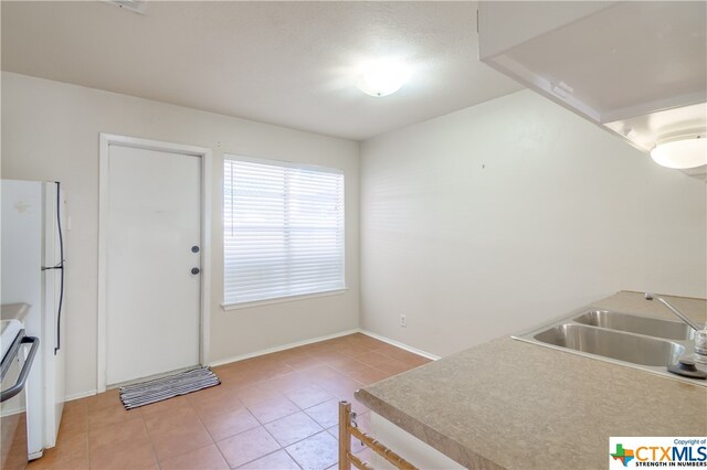 kitchen with white refrigerator, sink, and light tile patterned floors