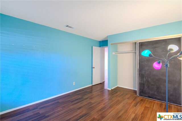 unfurnished bedroom with a closet and dark hardwood / wood-style flooring