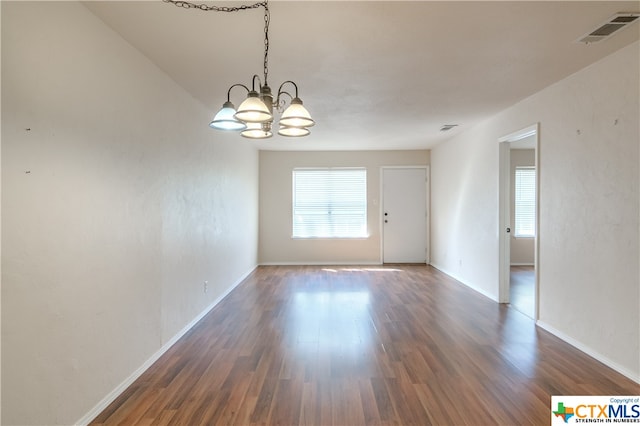 spare room featuring dark hardwood / wood-style floors and an inviting chandelier