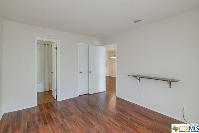 unfurnished bedroom featuring ensuite bathroom and dark hardwood / wood-style floors