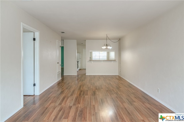 unfurnished room with hardwood / wood-style flooring and an inviting chandelier