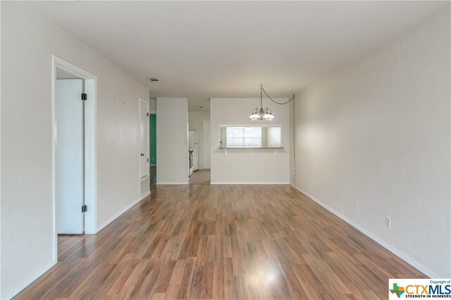 unfurnished room with hardwood / wood-style flooring and an inviting chandelier