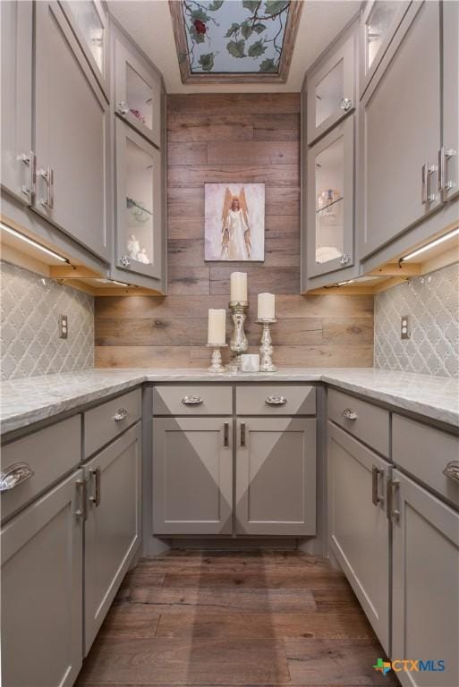 kitchen featuring tasteful backsplash, gray cabinets, light stone countertops, and dark wood-type flooring