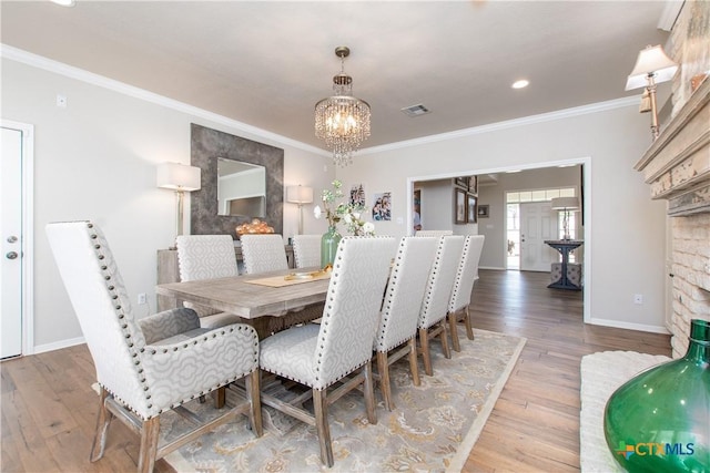 dining space with hardwood / wood-style floors, crown molding, and an inviting chandelier