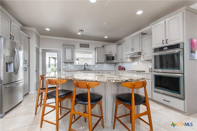 kitchen with appliances with stainless steel finishes, gray cabinetry, crown molding, sink, and a center island