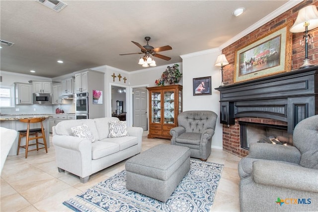 tiled living room with a brick fireplace, ceiling fan, a textured ceiling, and ornamental molding