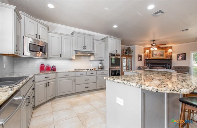 kitchen with ceiling fan, ornamental molding, tasteful backsplash, a kitchen island, and stainless steel appliances