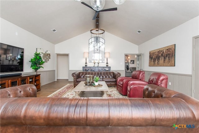 living room featuring ceiling fan with notable chandelier, vaulted ceiling, and hardwood / wood-style flooring