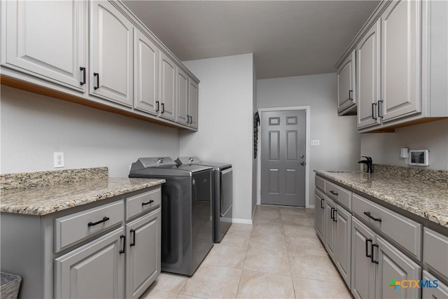 clothes washing area featuring cabinets, sink, light tile patterned flooring, and washer and dryer