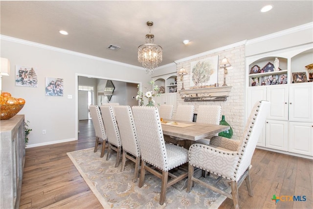 dining area featuring a chandelier, built in shelves, dark hardwood / wood-style floors, and crown molding