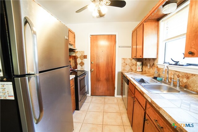 kitchen with stainless steel appliances, sink, tasteful backsplash, light tile patterned floors, and tile counters