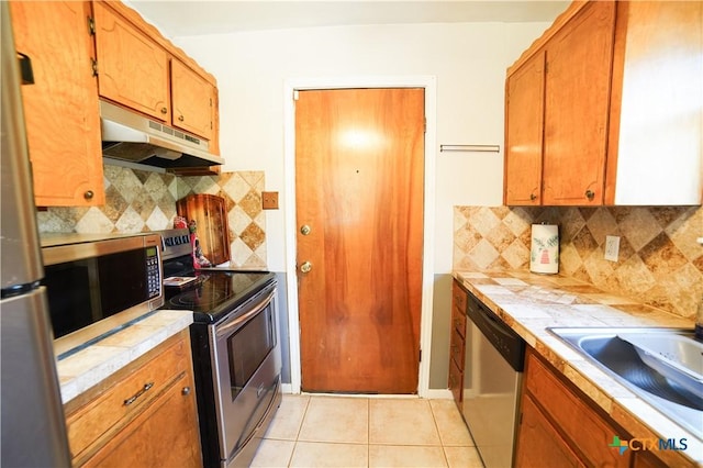 1106 Dryden Ave, Copperas Cove, TX 76522 - kitchen featuring under cabinet range hood, appliances with stainless steel finishes, tile counters, and backsplash