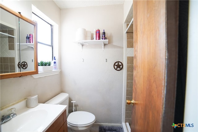 bathroom featuring toilet, vanity, and tiled shower